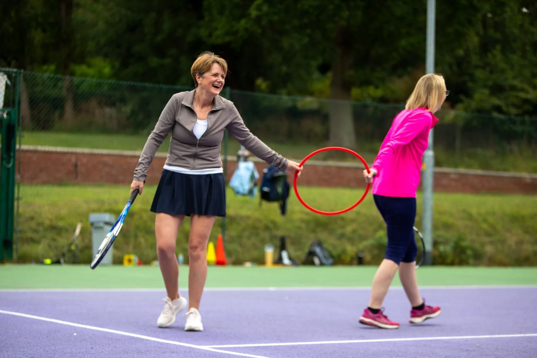 Adult tennis players smiling and chatting beside the net