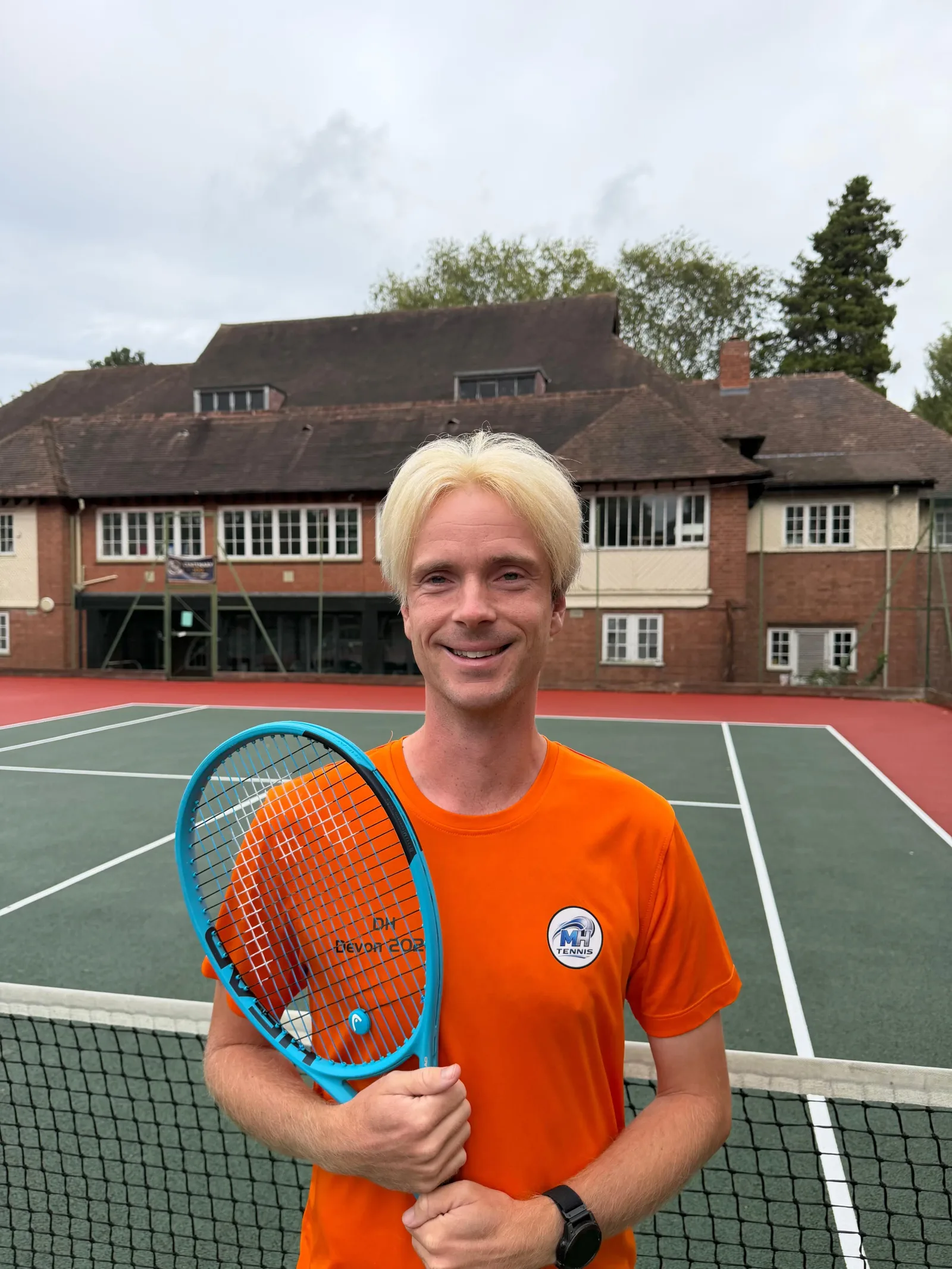 Dan Hillman, LTA-qualified Level 3 Tennis Coach, standing with a tennis racket on an outdoor tennis court