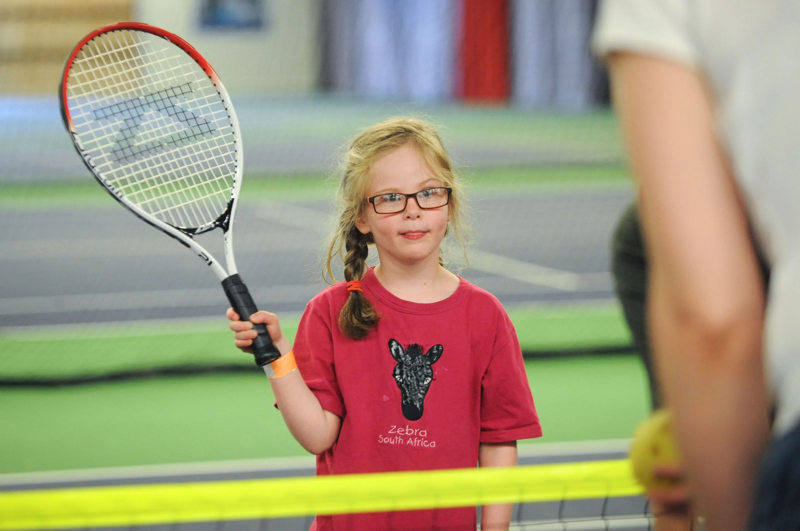 Young tennis player holding a racket indoors