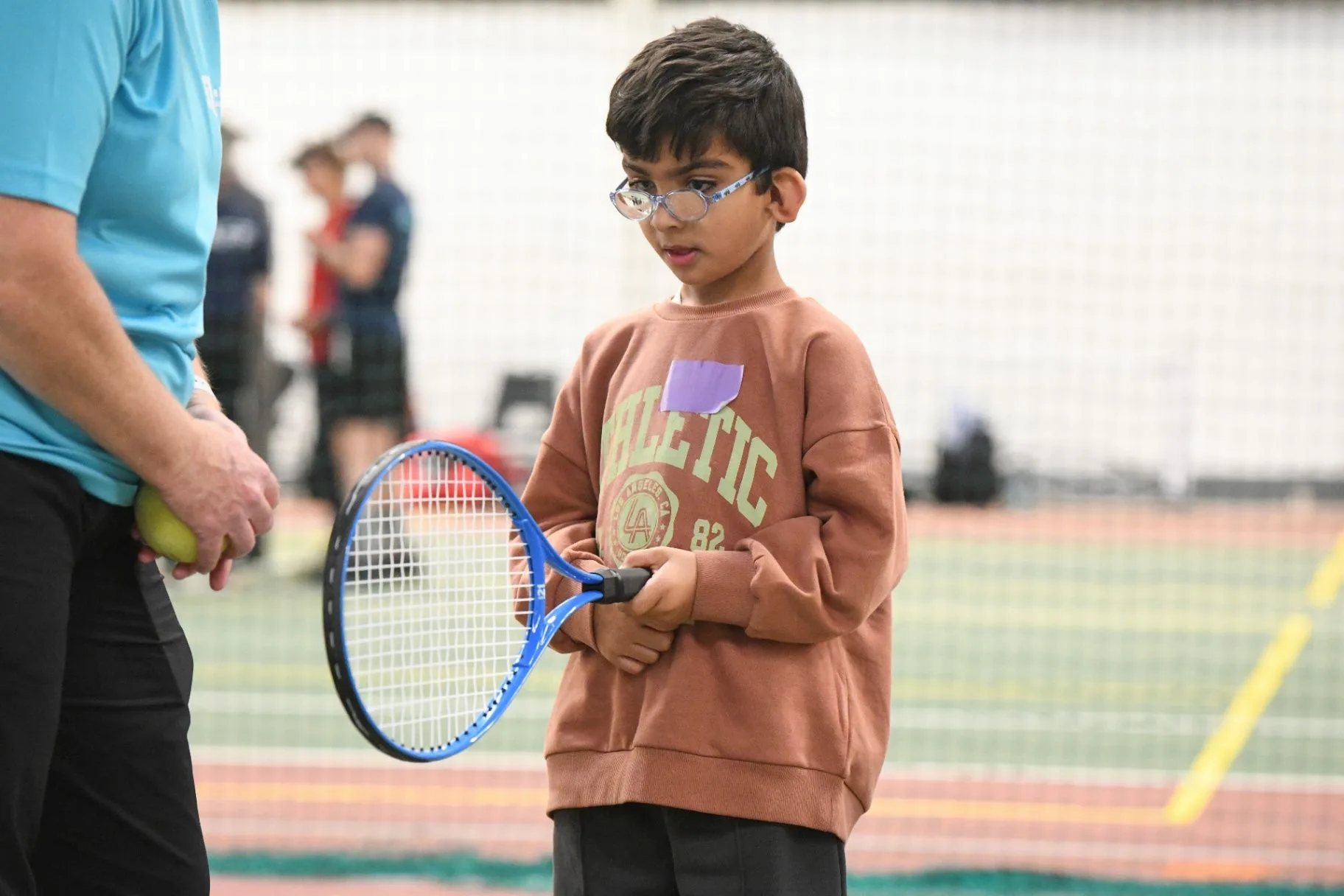 Young tennis player with a coach indoors