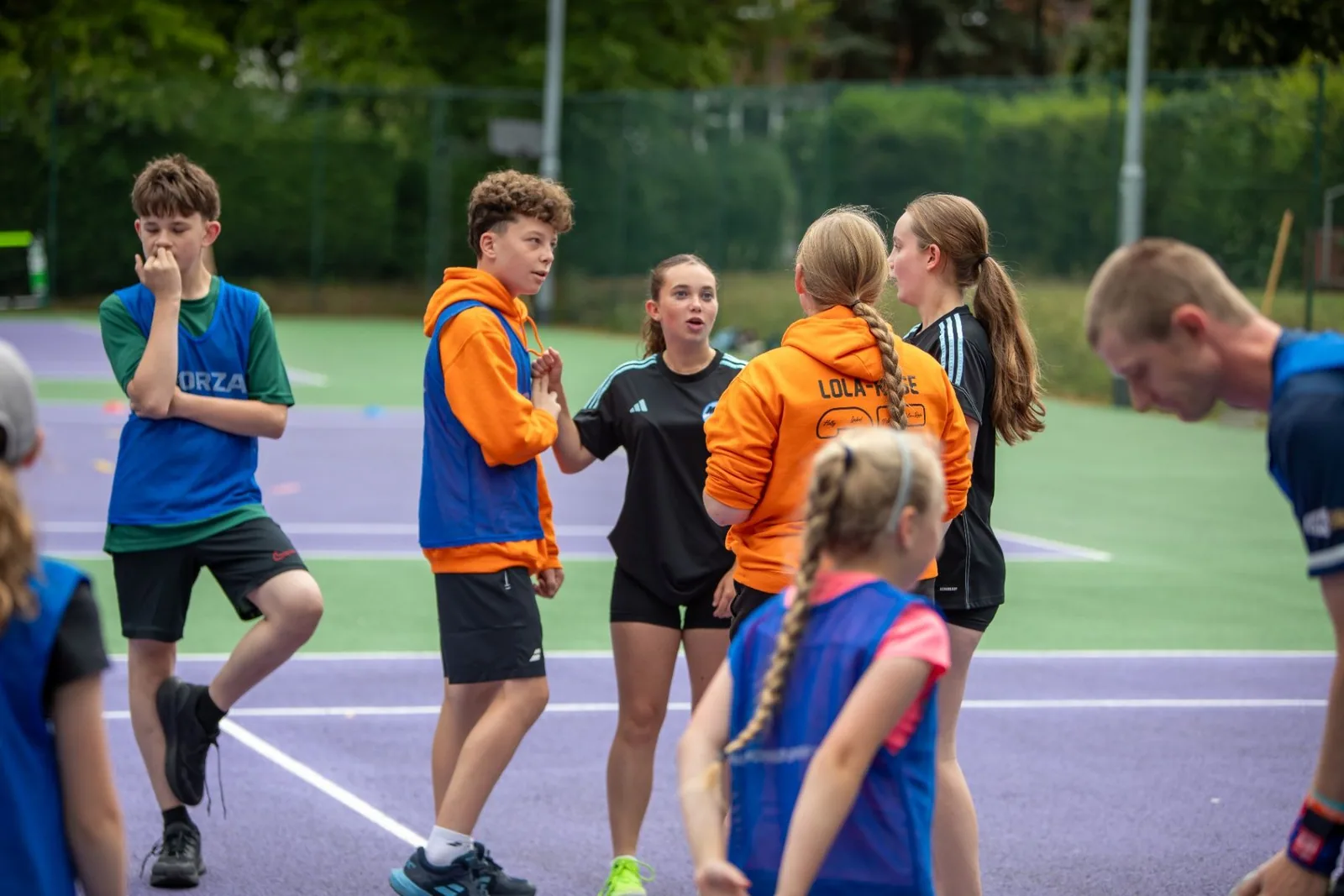 Young players gathering on an outdoor tennis court during a group activity