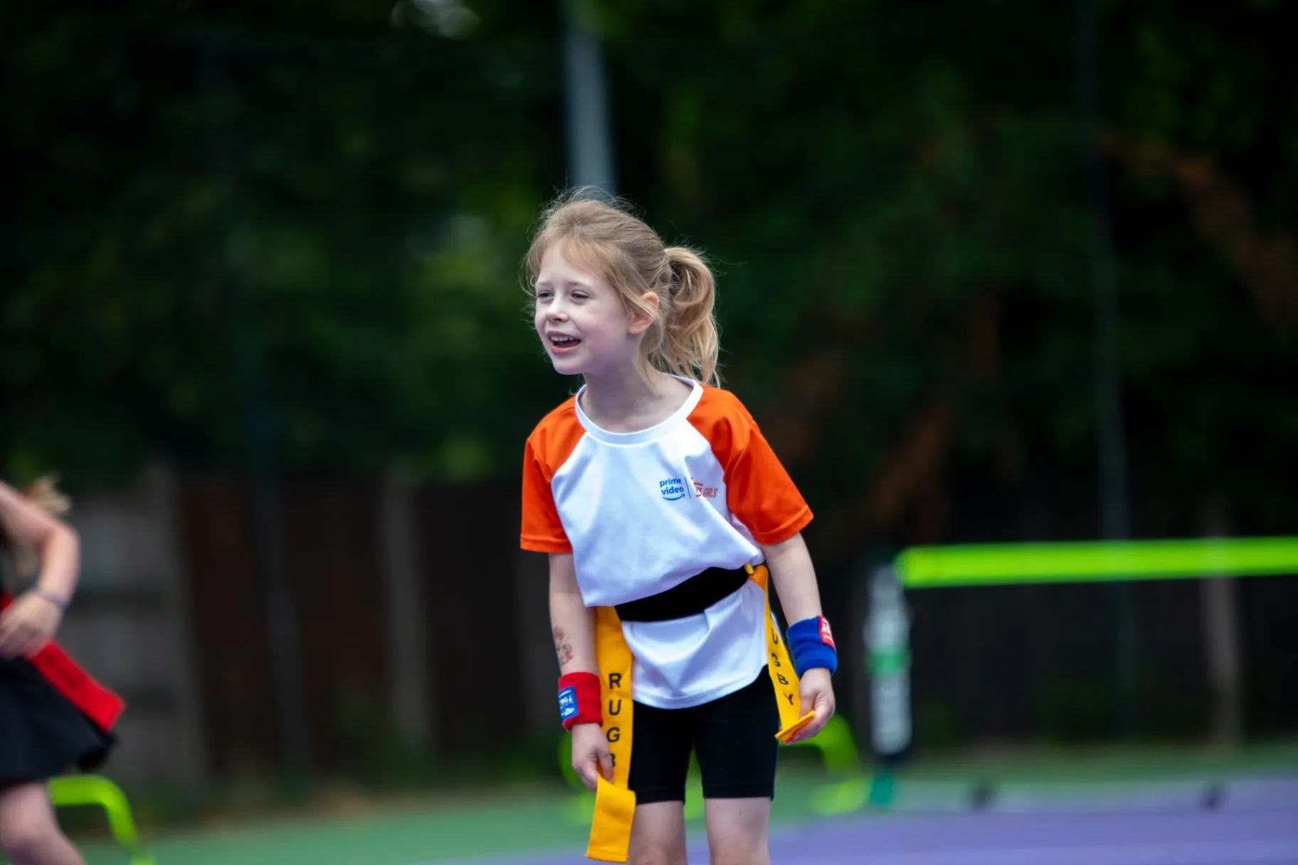 Young girl smiling with a tennis racket on an outdoor court