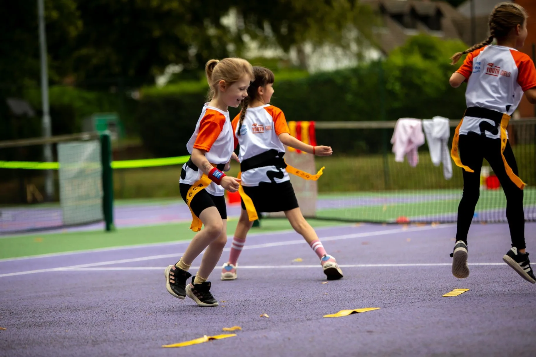 Two young girls moving across a tennis court during a coaching drill